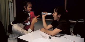 two women entertain a young girl playing with a flashlightby playing with a flashligh