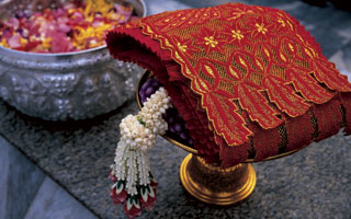 a Thai dancer shimmers in red and gold as she moves to the music