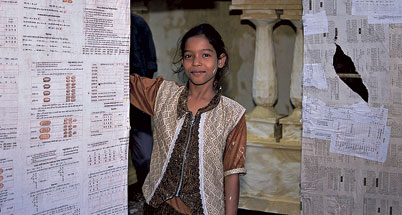 a girld stands in a doorway with newspapers attached to the door