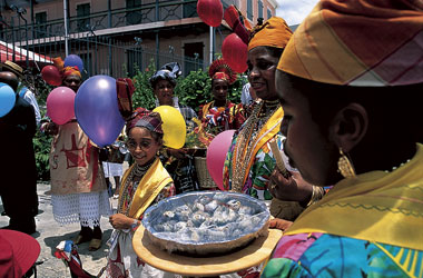 a Brazilian woman carries seafood to a table while a young girl looks on happily
